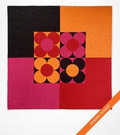 an orange, black, and pink patchwork quilt with circles on it's center