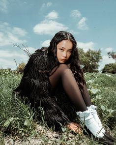 a woman sitting in the grass with her legs crossed