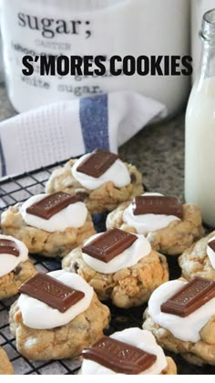 cookies with marshmallows and chocolate are on a cooling rack next to a glass of milk