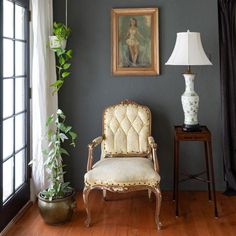 a living room with a chair, lamp and painting on the wall in it's corner