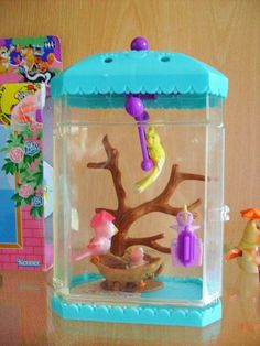 there is a small toy tree in a glass case on the table next to other toys