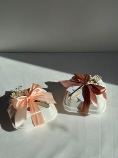 two small white shoes with bows on them