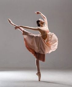 a ballerina in a pink dress is doing a ballet move with her arms stretched out