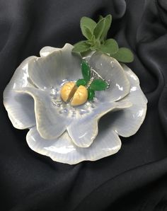 a white flower shaped dish with green leaves on the center and two yellow flowers in the middle