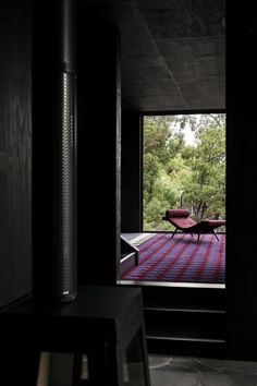 an open room with a chair and red rug on the floor in front of a large window