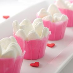 small cupcakes with white frosting and red hearts on a pink platter