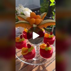 an image of desserts on a glass plate with flowers in the vase behind it