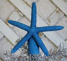 a blue starfish ornament sitting on top of a silver tinsel christmas tree