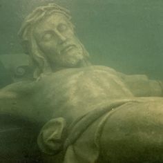 the statue is under water and it looks like he's floating on his stomach