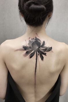 the back of a woman's neck with a flower tattoo on it