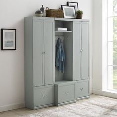 a grey armoire with two drawers and a coat hanging on the door, in front of a white wall