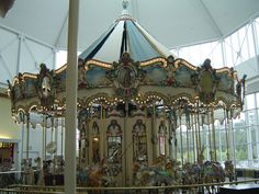 an ornately decorated merry go round in a large indoor area with high ceilings and glass windows