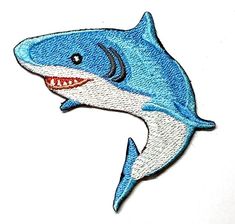 a blue and white shark with teeth on it's back, embroidered onto a white surface