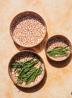 three bowls filled with green beans on top of a table