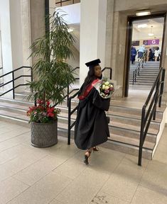 a woman in graduation gown walking down the stairs with flowers on her lap and holding a bouquet