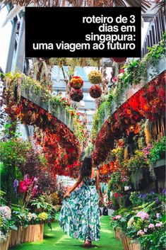 a woman walking through a garden filled with lots of plants and hanging baskets full of flowers