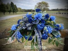 a bouquet of blue flowers sitting on top of a wooden fence next to a field