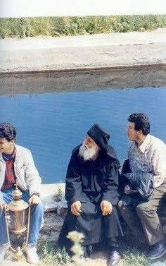 three men sitting next to each other near water