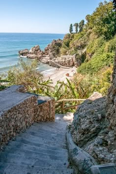 stairs lead down to the beach from an old stone building with steps leading up into the water