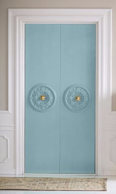 a blue door with two round knobs on the front and side panels, in an empty room