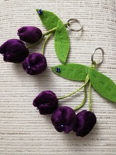 two purple flowers are attached to green leaves on a white surface with blue beads in the middle