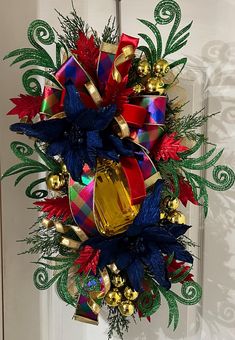 a christmas wreath hanging on the front door decorated with red, green and gold decorations