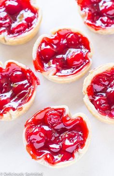 small pastries with jam on them sitting on a white table top next to each other