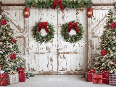 three christmas wreaths and presents in front of an old barn door with red bows