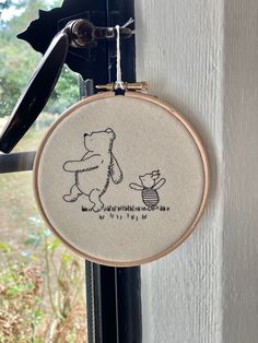 a cross stitch winnie the pooh and piglet hanging from a window sill