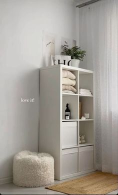 a white shelf with towels and other items on it in a small room next to a window