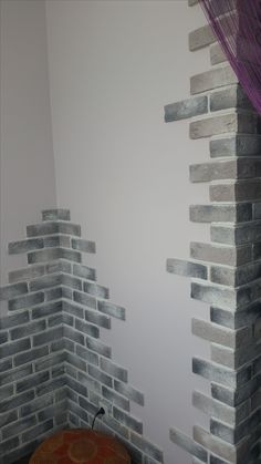 a room with white brick walls and purple drapes on the window sill next to a round table