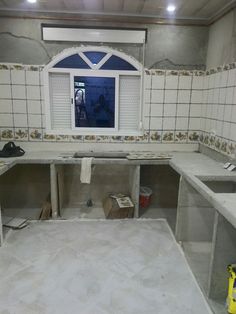 an unfinished kitchen with white tile walls and counters