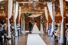 a bride and groom standing at the end of their wedding ceremony in an old barn