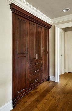 an empty room with wooden cabinets and hard wood flooring, along with white walls