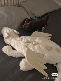 two stuffed animals laying on top of a bed next to pillows and a pillow case