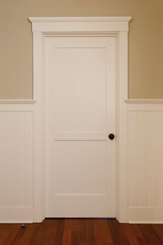 an empty room with a white door and wooden floors