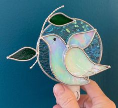 a hand holding a stained glass bird decoration