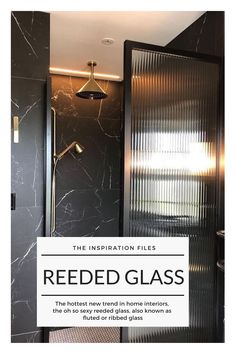 the inside of a bathroom with black marble walls and flooring, including a glass shower door