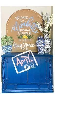 a blue painted dresser with vases and flowers on top