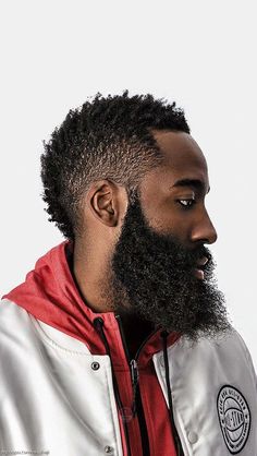 a man with a full beard wearing a white jacket and red hoodie looking off to the side