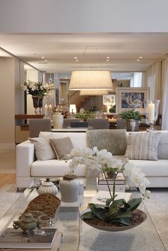 a living room filled with lots of furniture and flowers in vases on the coffee table