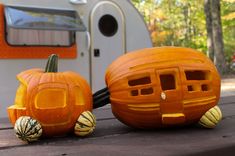 two carved pumpkins sitting on top of a picnic table next to a white trailer