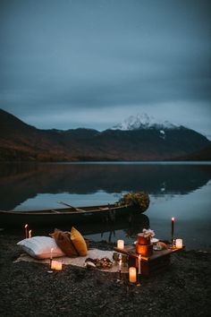 a boat sitting on top of a lake next to a blanket and some lit candles