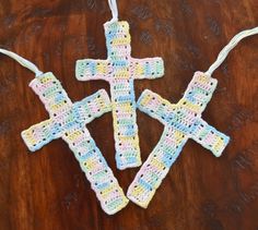 three crocheted crosses hanging on a wooden table