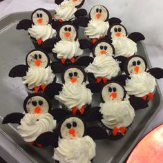 cupcakes with white frosting and black icing are arranged in the shape of penguins