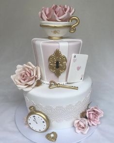 a three tiered cake with pink roses and cards on the top is decorated in gold