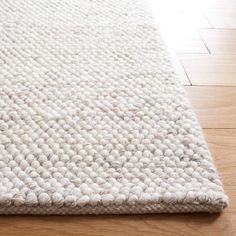 a white rug is laying on the floor in front of a wood flooring area