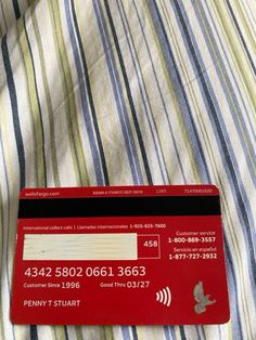 a red credit card sitting on top of a striped bed sheet in a hotel room