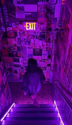 a woman walking up some stairs with purple lights