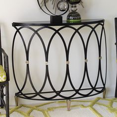 a black console table sitting on top of a rug next to a wall mounted clock